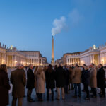 Comment comprendre l’élection de Léon XIV et les enjeux de son pontificat ? La place Saint-Pierre au Vatican au crépuscule, avec une foule discrète observant une légère fumée blanche dans une atmosphère solennelle.